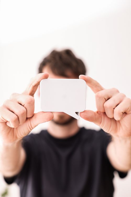 Free Male holding a blank speech bubble card with both hands, focus on object. Stock Photo