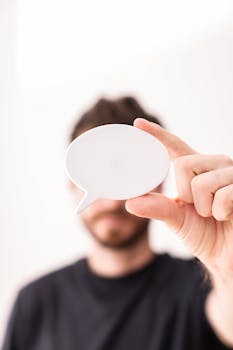 Close-up of a man holding a blank speech bubble card, perfect for mockups and messages.