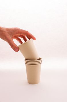 Close-up of hand stacking biodegradable paper cups, emphasizing sustainability. — photo by Cup of  Couple