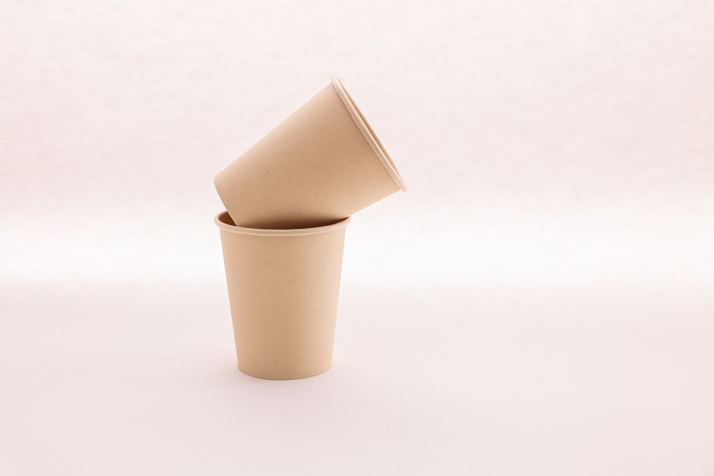 Two stacked kraft paper coffee cups on a pale backdrop, photo by Cup of Couple on Pexels