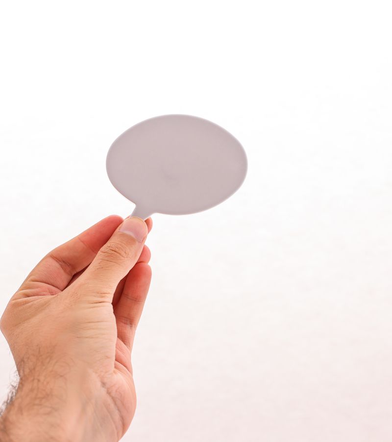 Fotografía de un adhesivo blanco sostenido en la mano con el logotipo TimeParche superpuesto como mockup