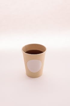 Simple disposable coffee cup with blank label against a soft white backdrop. Perfect for branding mockups.