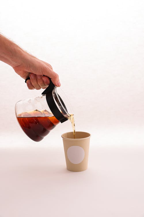 A Person Pouring Coffee to a Disposable Cup 