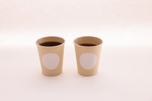 Two paper cups with coffee on a neutral backdrop, perfect for business branding mockups.