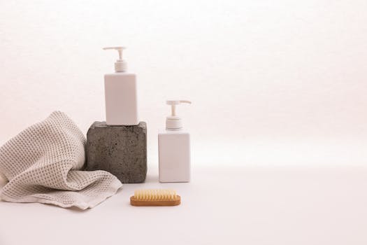 Minimalist still life featuring pump bottles and towel with copy space on white background.