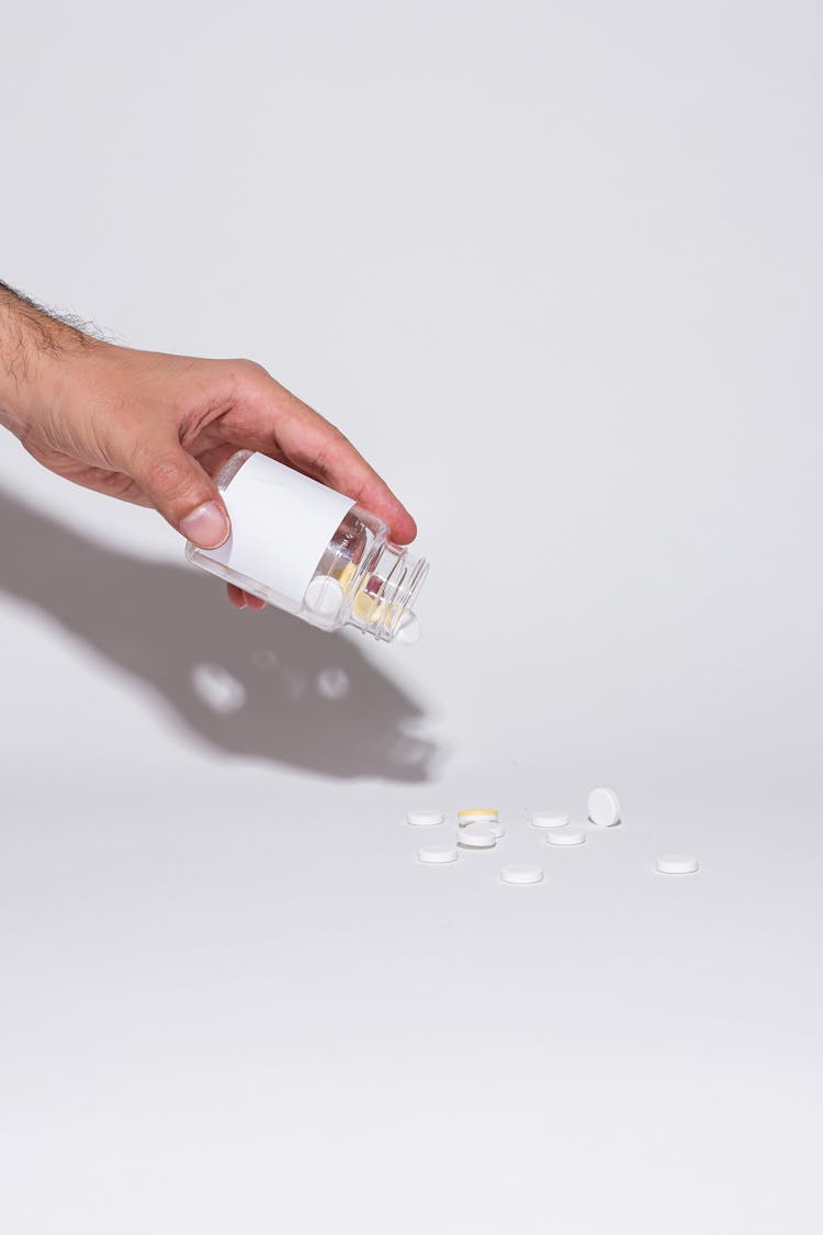 A Person Holding Glass Bottle With Pills