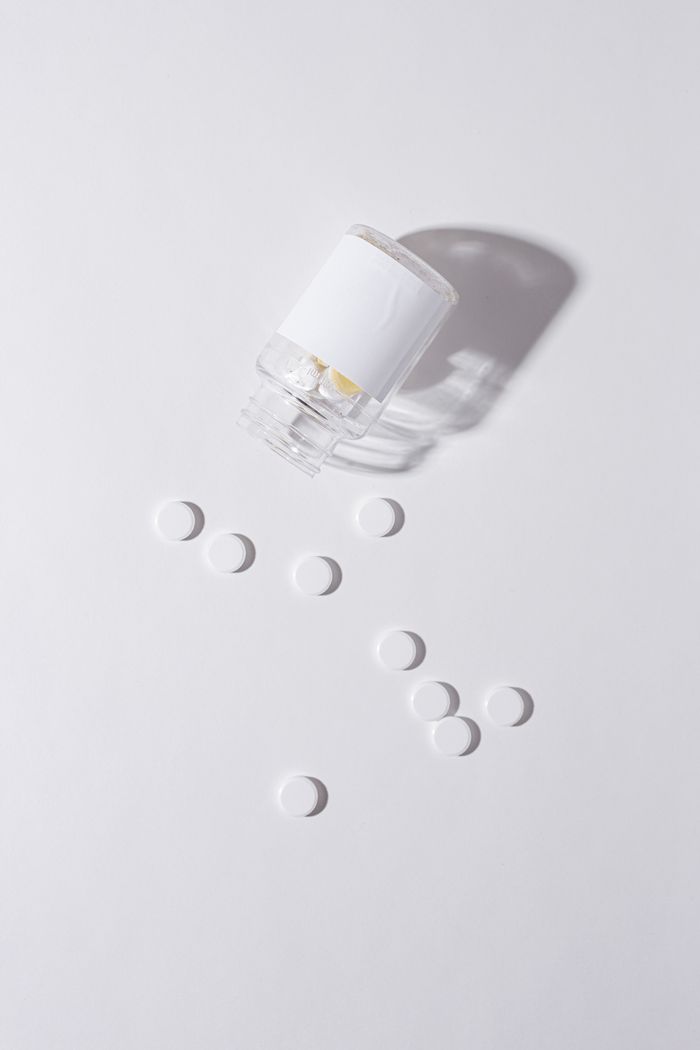 White tablets spilling from a pill bottle on a pale grey surface