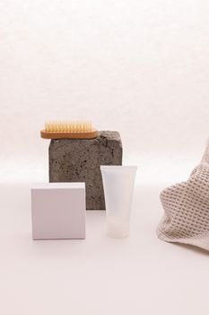Still life of beauty products with a minimalist aesthetic including a tube cream and brush on white background.