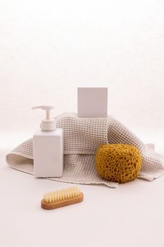 Elegant display of bath essentials including lotion pump, sponge, brush, and towel for skincare.