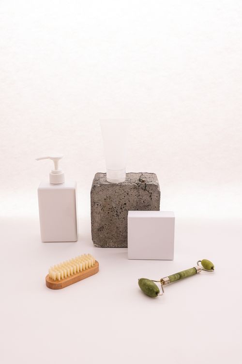 Free A collection of minimalist bath accessories including a jade roller, white dispenser, and bath brush. Stock Photo