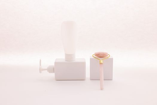 Minimalist skincare product arrangement featuring a jade roller and white dispenser.