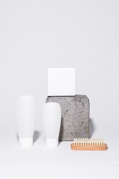 Simple minimalist setup of beauty products and brush on a stone block.