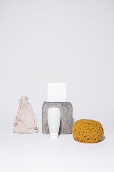 Minimalist setup featuring skincare items, sponge, and pouch on white background.