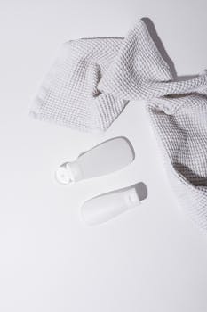 White plastic bottles and a textured towel on a clean surface, minimalist aesthetic.