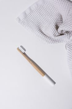 Top view of a sustainable bamboo toothbrush on a textured white towel.