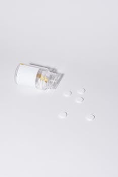 Clear medicine bottle with pills spilled on a white surface, emphasizing healthcare concepts.