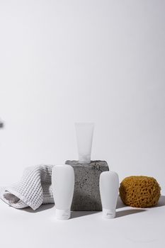 A clean and elegant spa setup with cosmetic bottles, sponge, and towel on a white background.