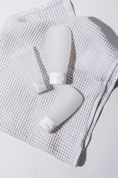 Three white lotion tubes displayed on a textured cloth in a clean, minimalist setting.
