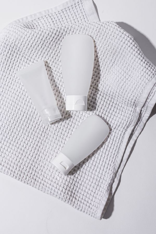 Three white lotion tubes on textured cloth — photo by Cup of Couple on Pexels