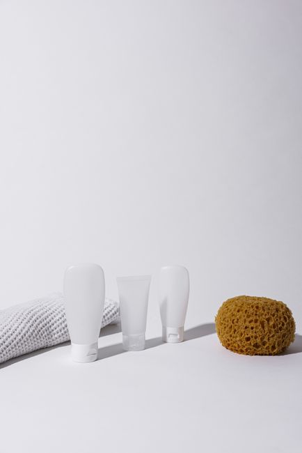Simple arrangement of bottles, sponge, and towel on a clean white background.