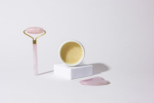 Minimalist setup featuring a jade roller and face cream for a luxurious skincare routine.