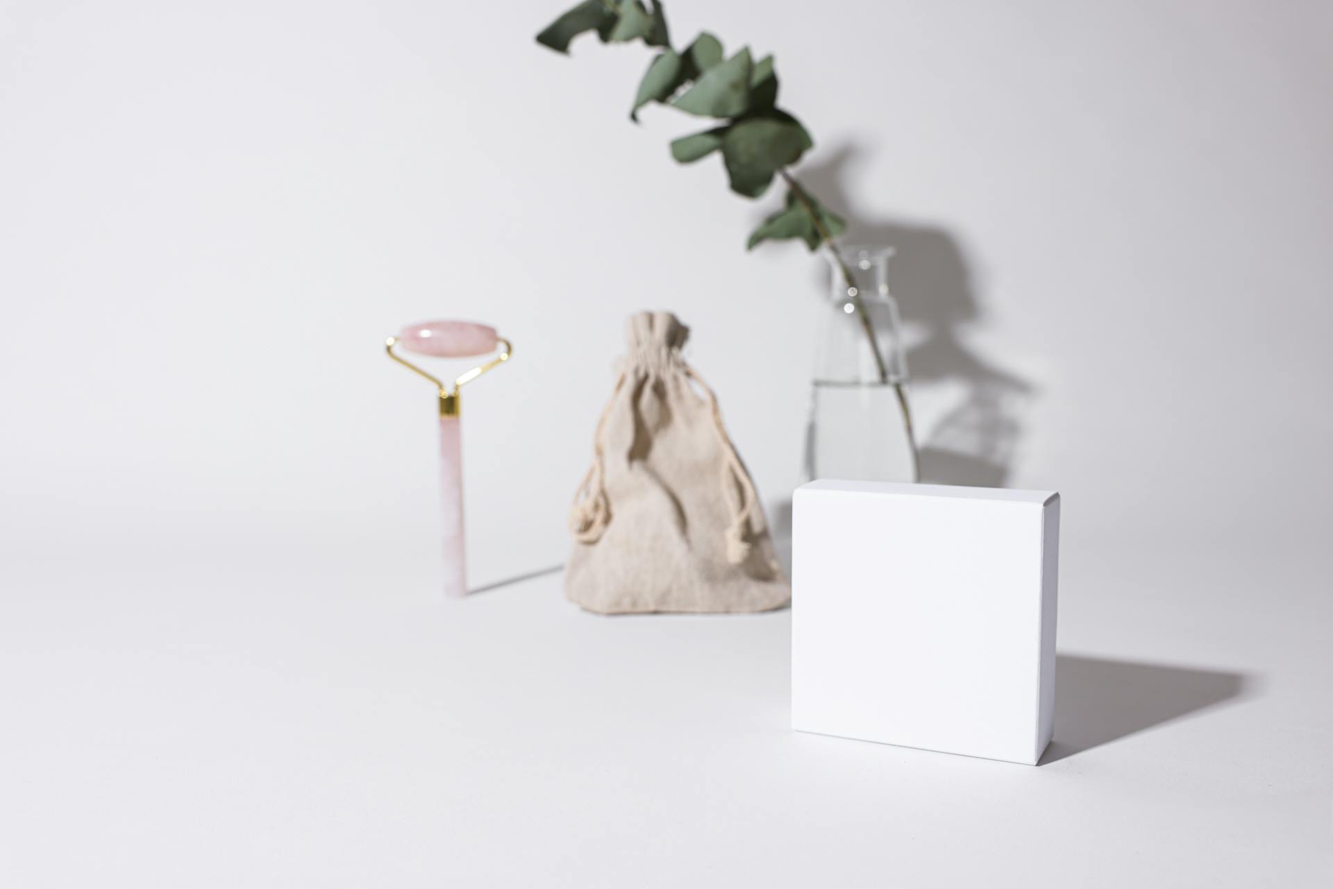 A Mockup of a White Box in Front of a Pouch and a Cosmetic Roller
