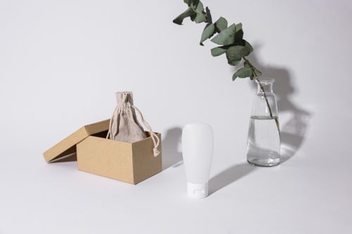Free A minimalist composition showcasing a box, cream container, and eucalyptus branch on a white background. Stock Photo