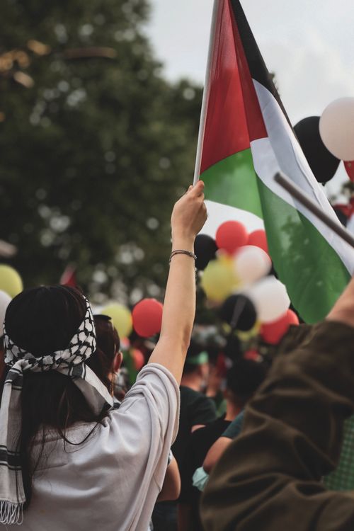 Free A lively street protest with a flag waving in the crowd amidst colorful balloons, symbolizing unity and activism. Stock Photo