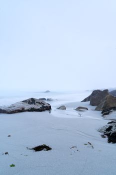 Serene misty seashore with rocks and sand at Sambro Creek, capturing a cool and tranquil atmosphere.
