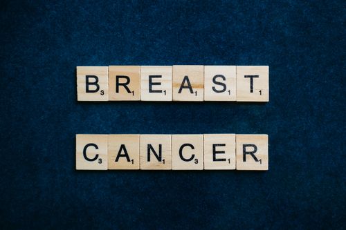 Free Wooden Scrabble tiles spelling 'Breast Cancer' on a dark blue background. Stock Photo