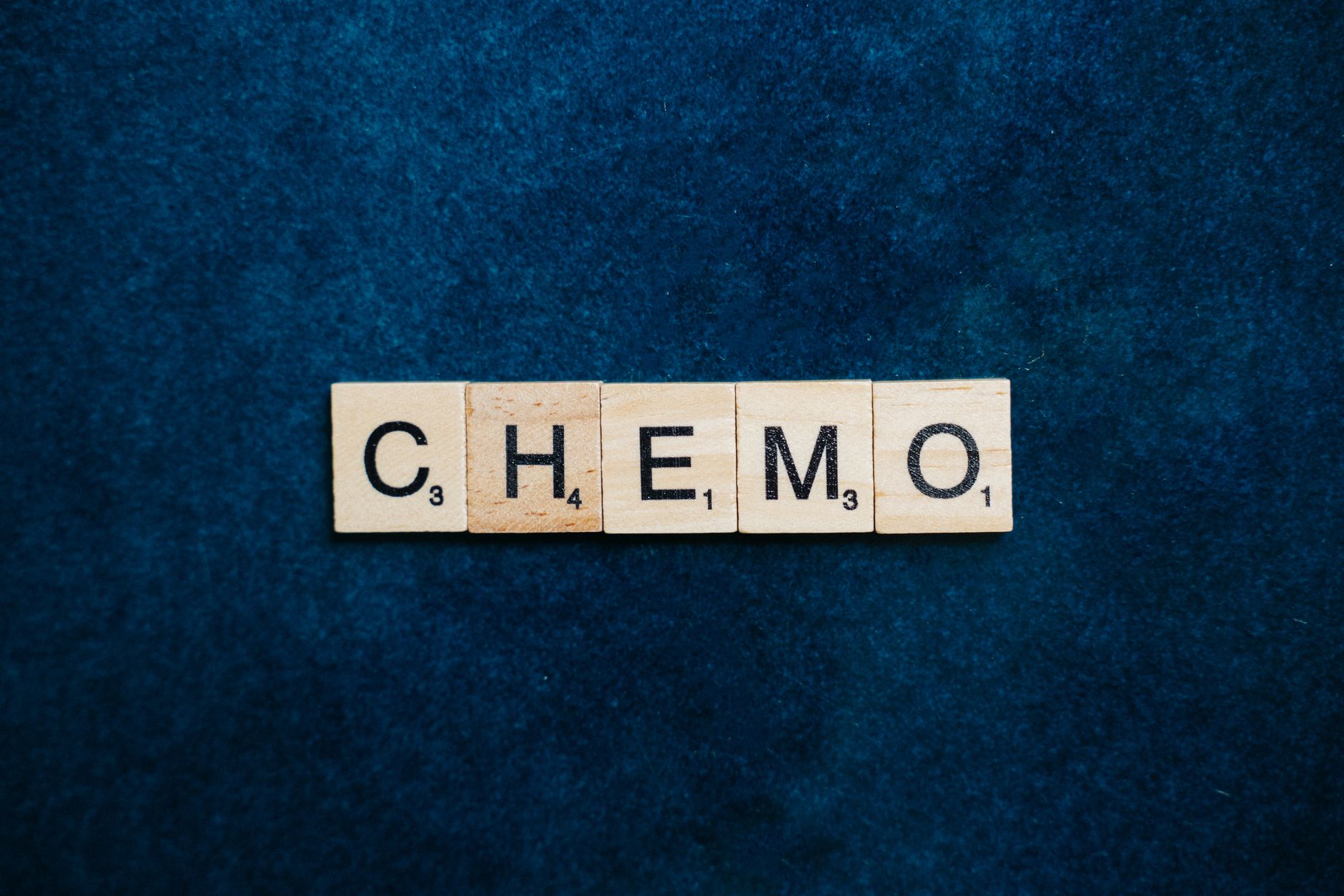 fenbendazole dosing for glioblastoma — Close-up of Scrabble tiles spelling 'CHEMO' on a dark blue textured background.