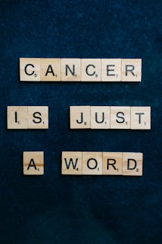 Motivational message "Cancer is just a word" spelled out with Scrabble tiles.