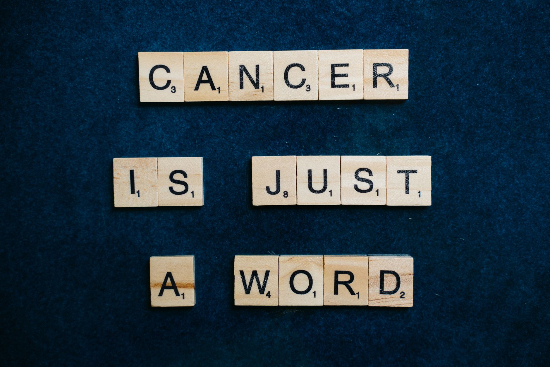 암보험 보험금 청구, 복잡한 서류 준비 한 번에 끝내기 5 Scrabble tiles spelling 'Cancer is just a word' on a blue background promoting hope and support.