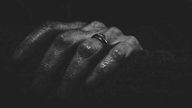 Artistic monochrome photo of an aged hand adorned with a metallic ring.