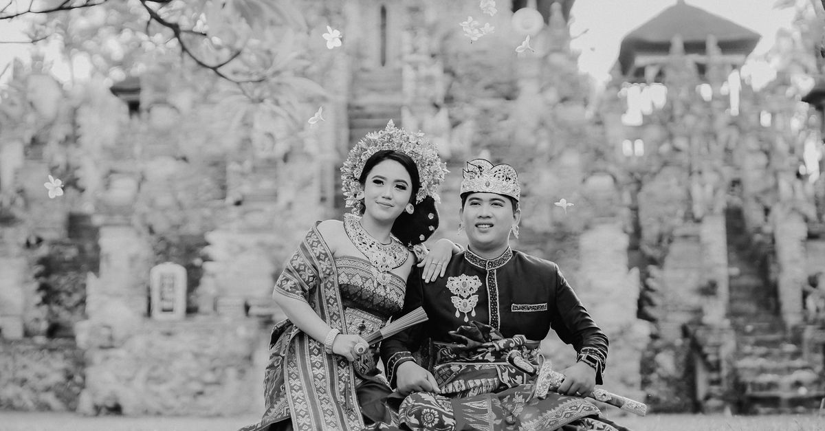 A couple in traditional attire at a historical site, celebrating their cultural heritage in style.