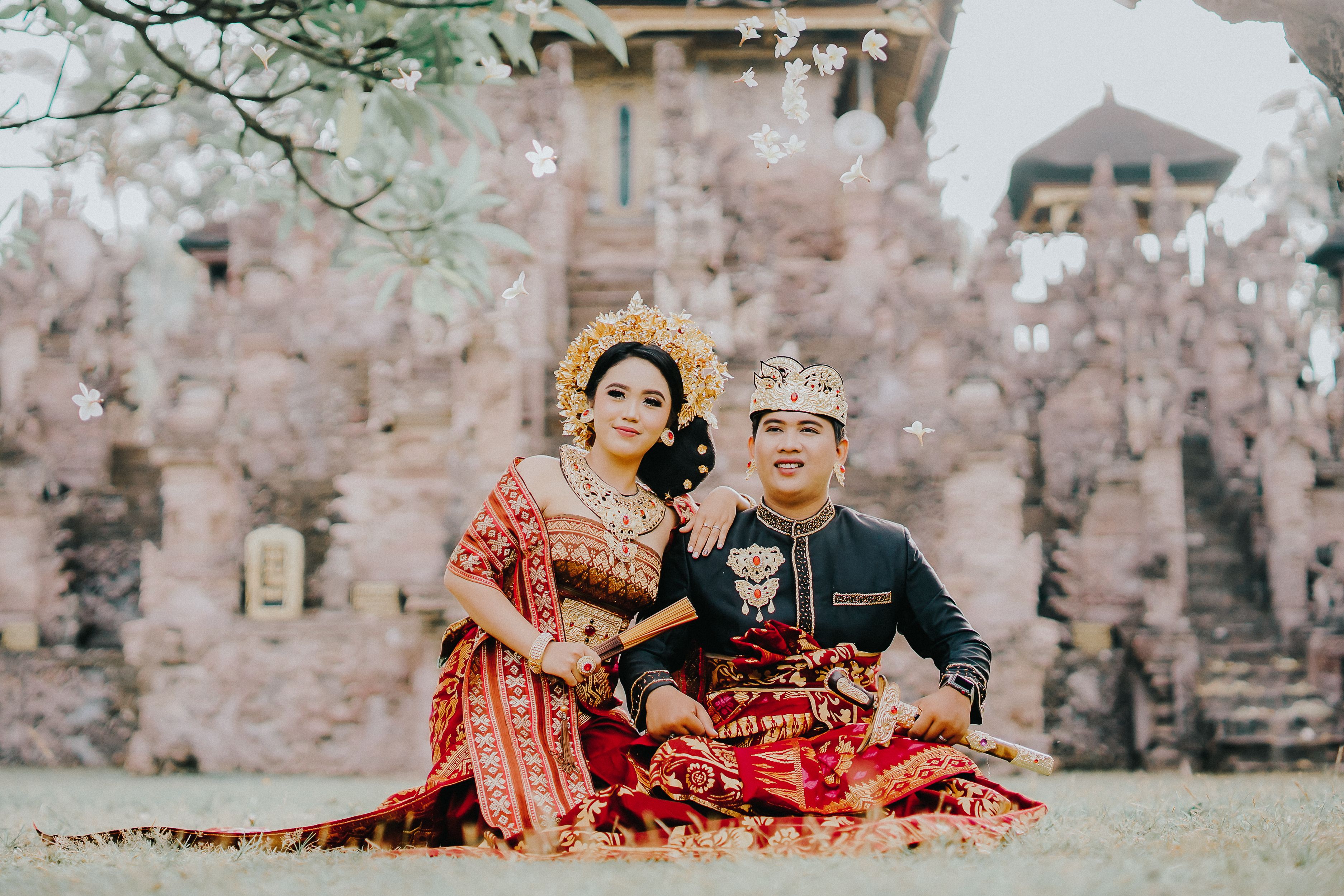 Elegant traditional couple portrait in cultural attire with ornate temple backdrop.