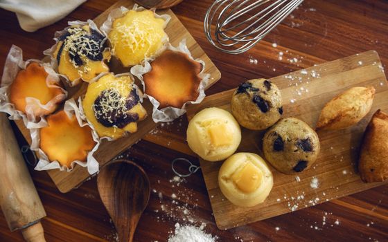A delicious assortment of muffins and pastries displayed on wooden boards for a rustic food photography look.
