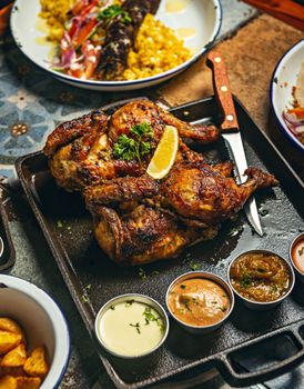Grilled chicken served with a variety of sauces and sides on a rustic platter.