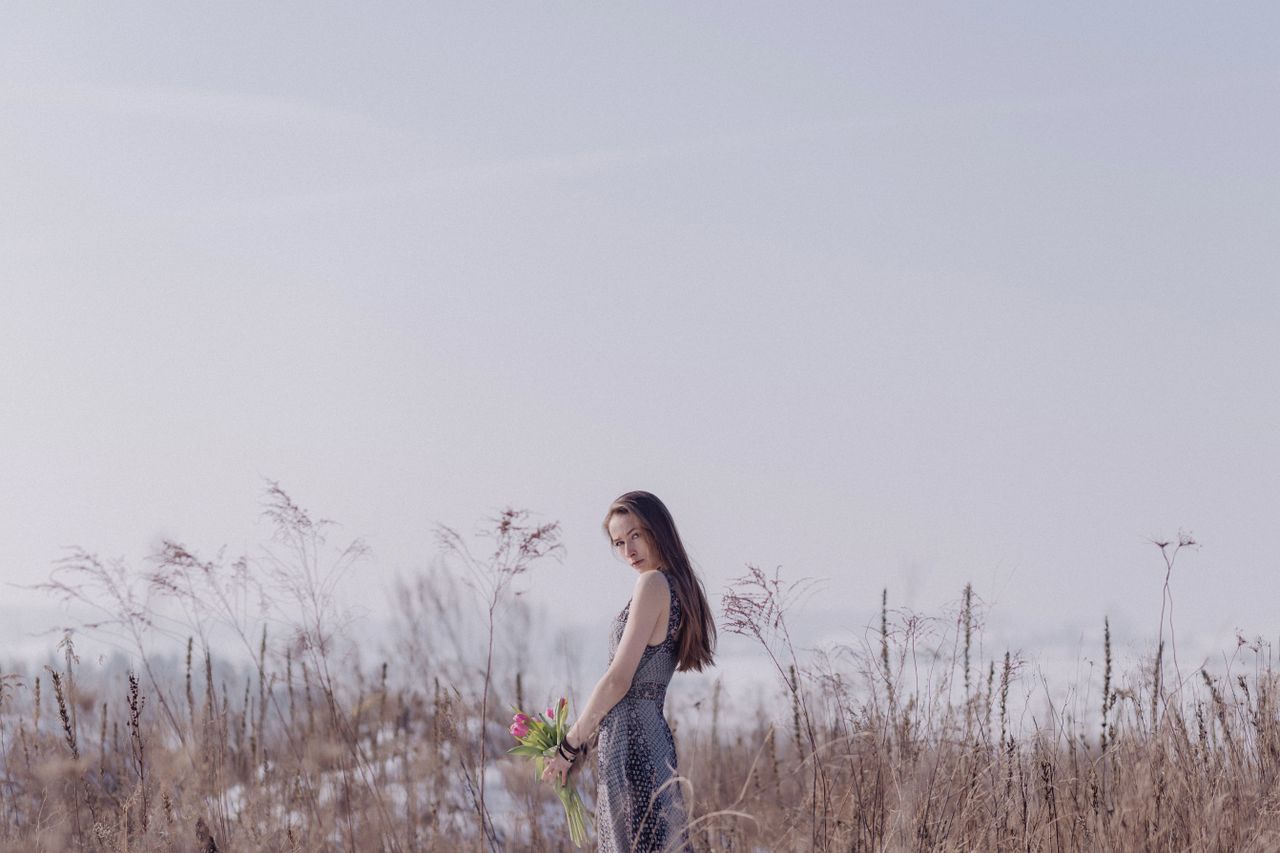 a serene scene of a woman holding flowers in a field embodying tranqui