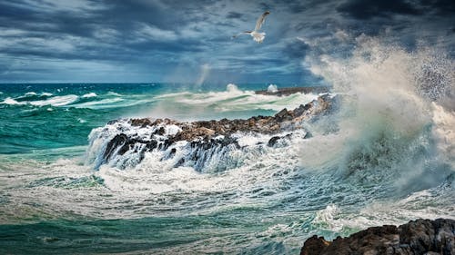 Beach Beside Stone Formation With Waves at Daytime