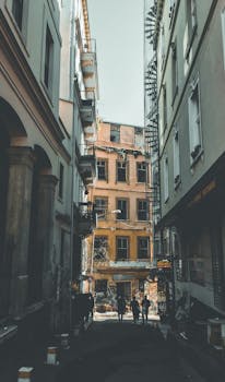 Charming urban alleyway with people walking among historic architecture and apartment buildings.