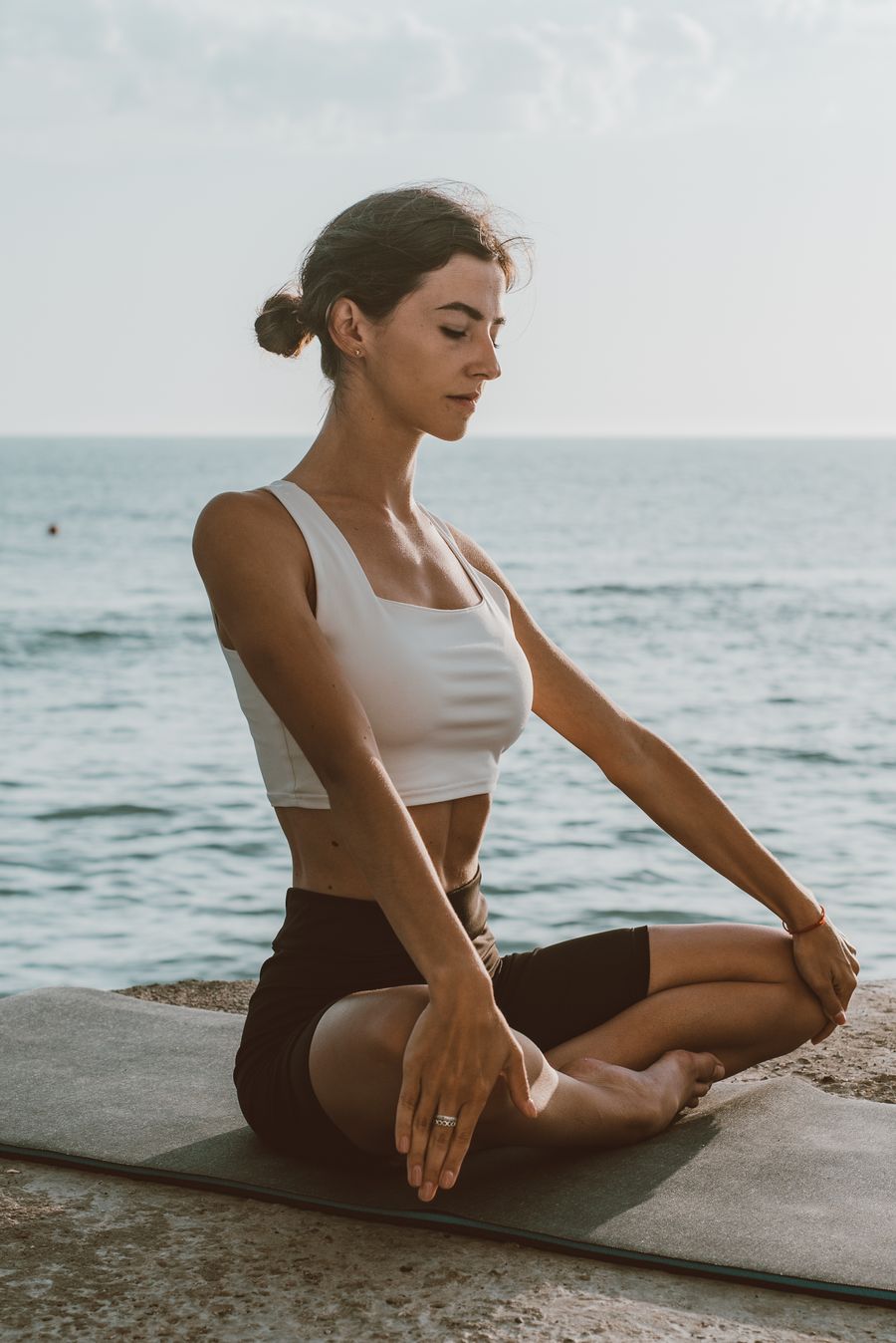 Woman meditating calmly by the sea to reduce stress naturally