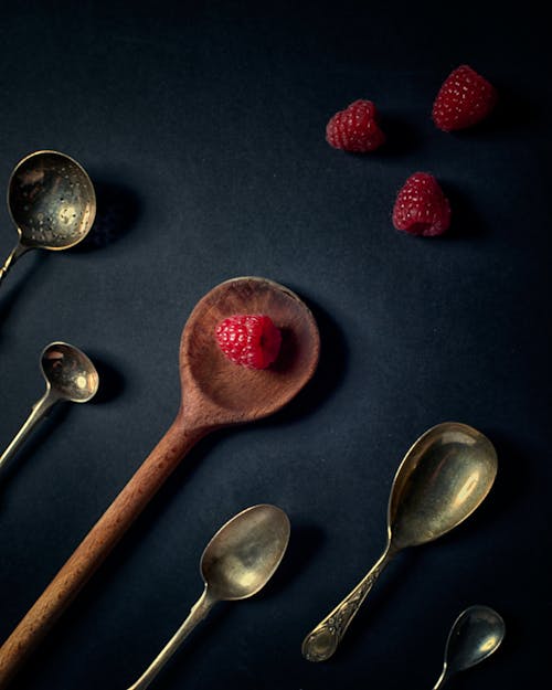 Red Strawberries and Stainless Steel Spoons on a Black Surface