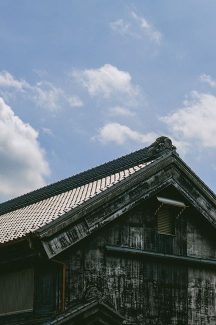 Close-up of an ancient Japanese roof showcasing intricate details with a blue sky background.