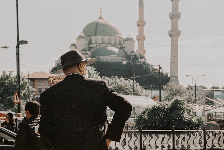 Man In Hat Standing With Mosque In Background