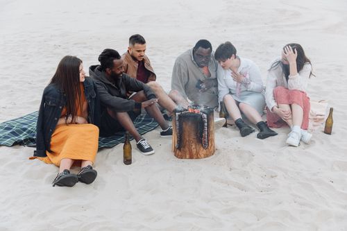 Free A group of friends sitting around a beach bonfire enjoying leisure time together. Stock Photo