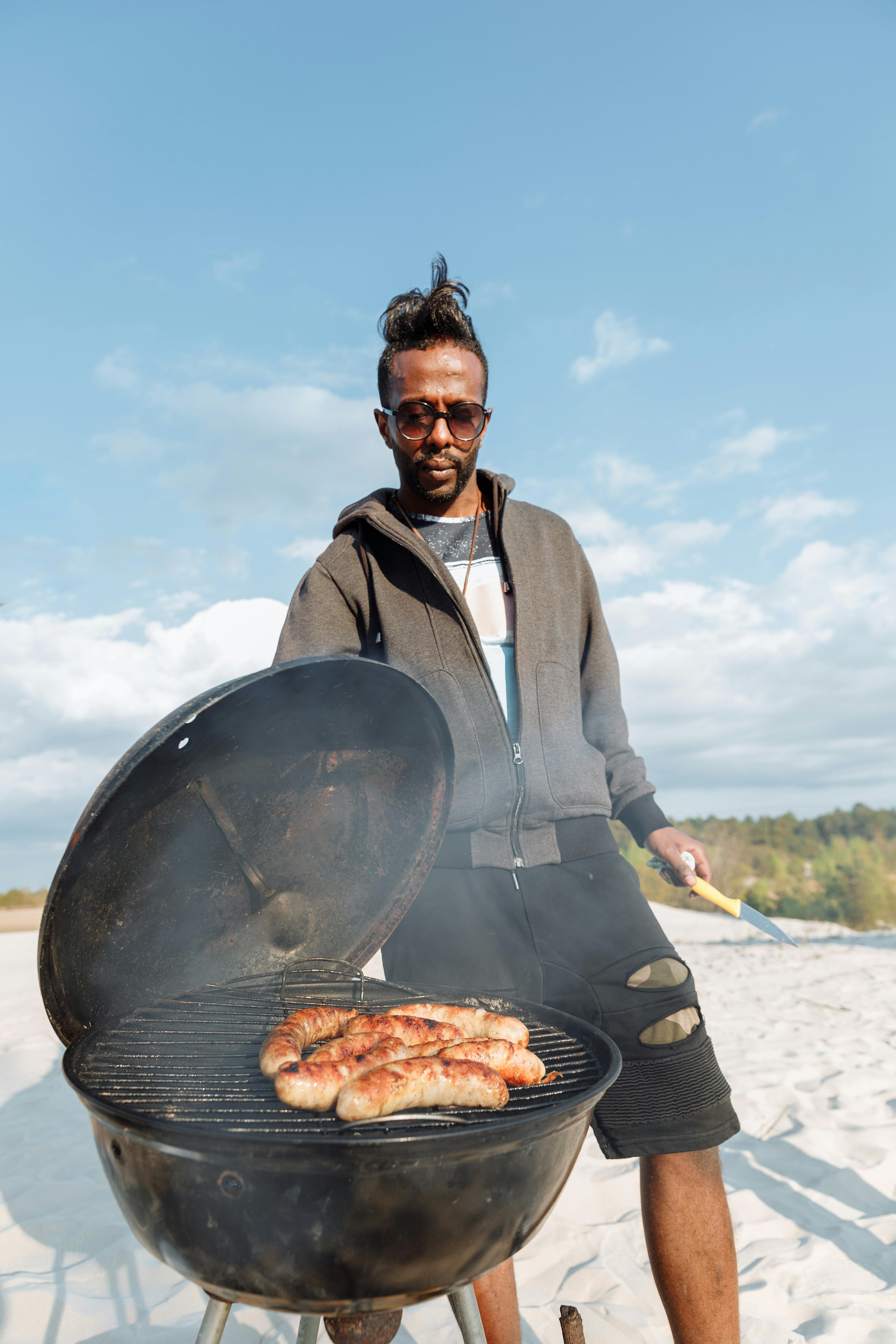 a man roasting sausages on a griller