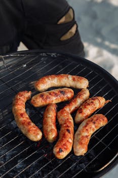 Close-up of delicious sausages grilling over charcoal, perfect for summer barbecues.