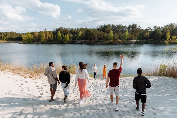 People Standing On Sandy Ground Near The Lake