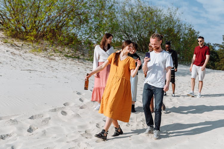 Group Of People Walking On White Sand